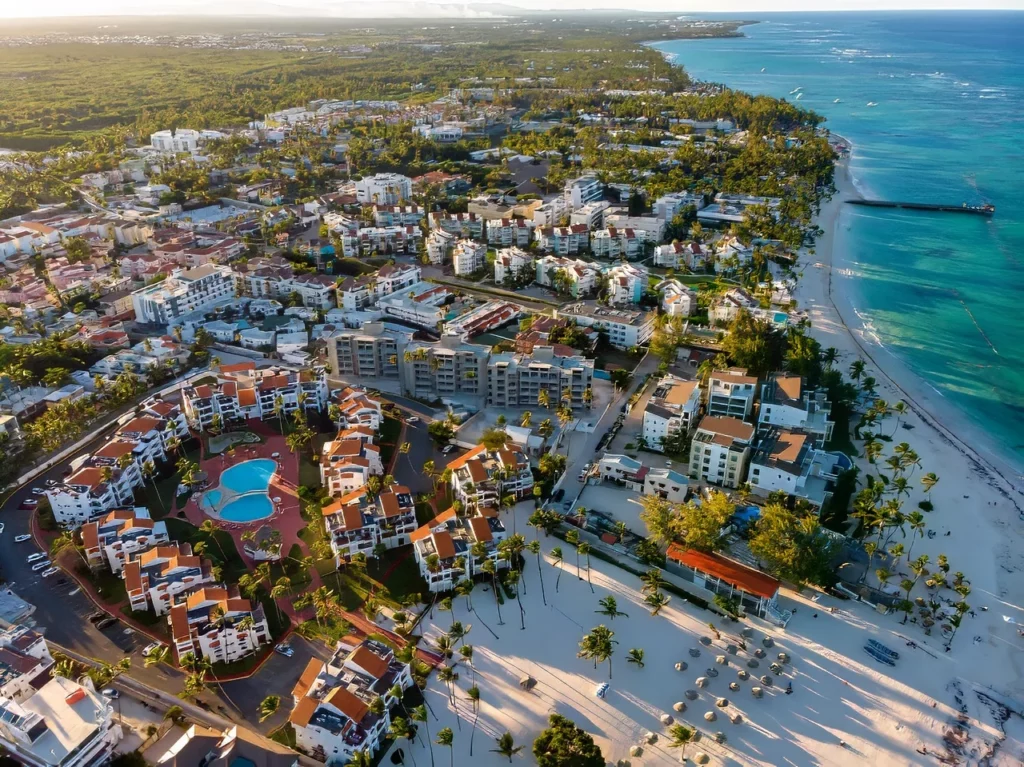 Aerial drone view of beach resort hotels with pools, umbrellas and blue water of Atlantic Ocean in Punta Cana, one of the featured destinations in our Dominican Republic travel guide.