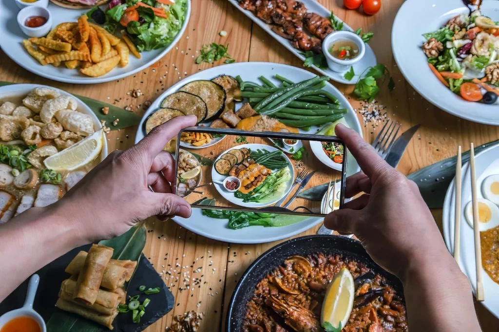 A person takes a close-up photo of various Filipino dishes on a plate in a restaurant with farm-to-table menus in the Philippines.