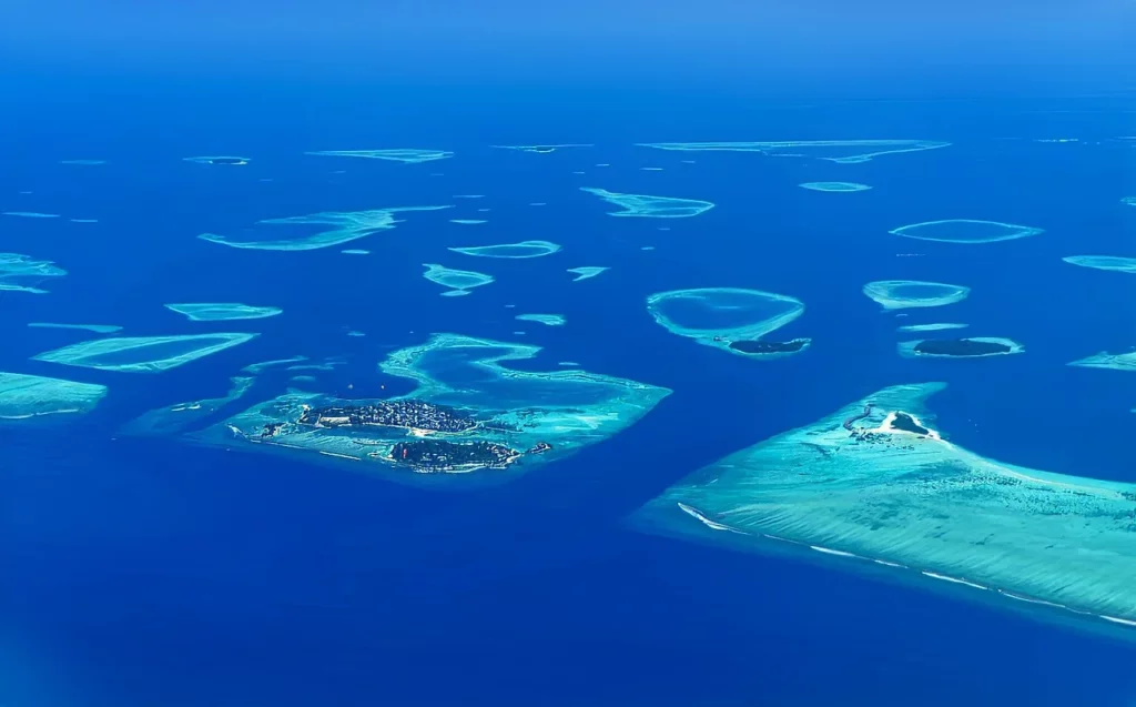 This is how the Maldives look from high above on a clear day, showing the islands featured in this travel guide.