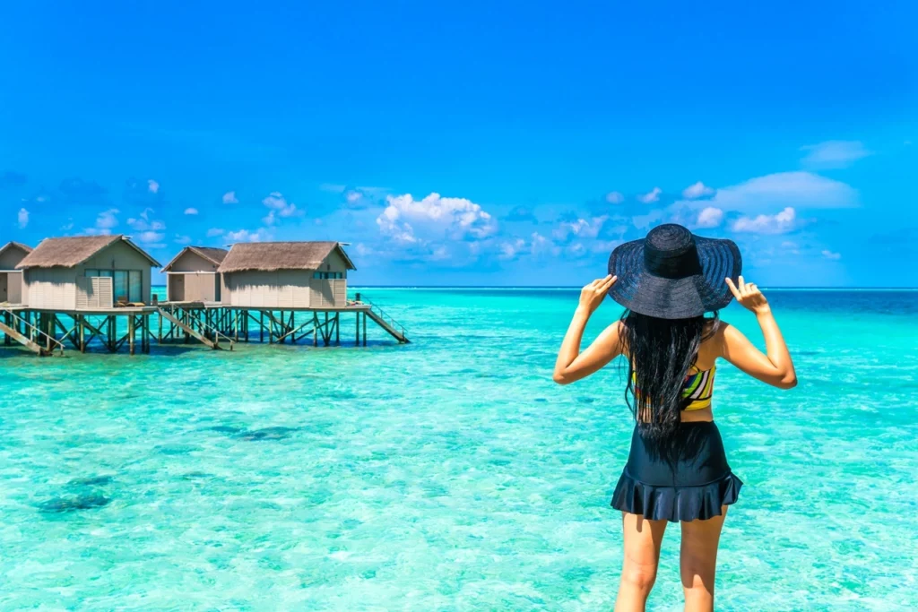 A tourist with a hat gazing at the horizon amid turquoise waters and overwater bungalows in Tahiti, one of the best places to visit in French Polynesia.