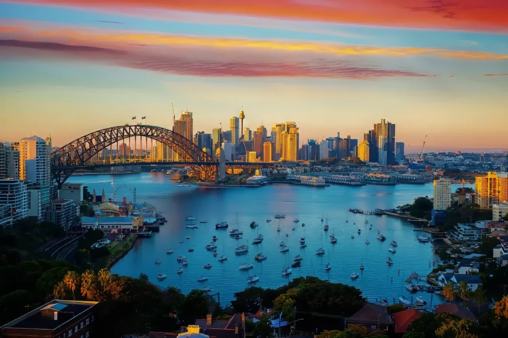 Red, orange, and yellow clouds over Sydney Harbour and Bridge at sunset, one of the destinations highlighted in this Australia travel guide.