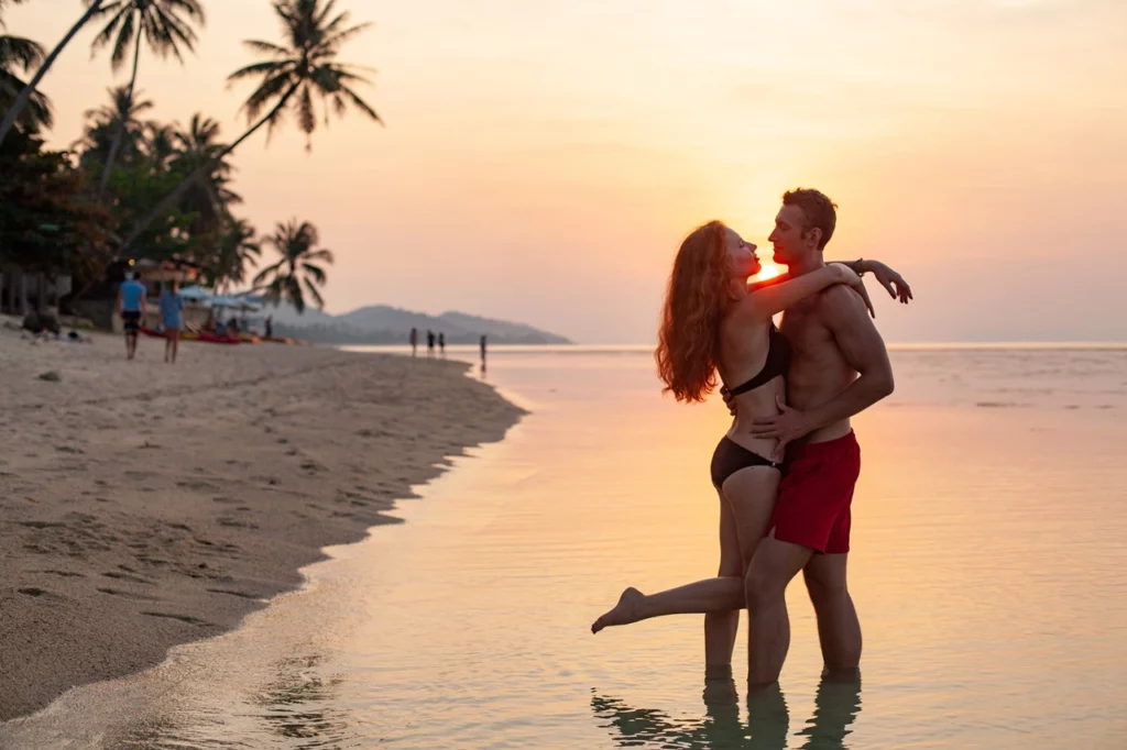 A couple embracing at the beach at sunset in one of the best wedding and honeymoon spots in French Polynesia.