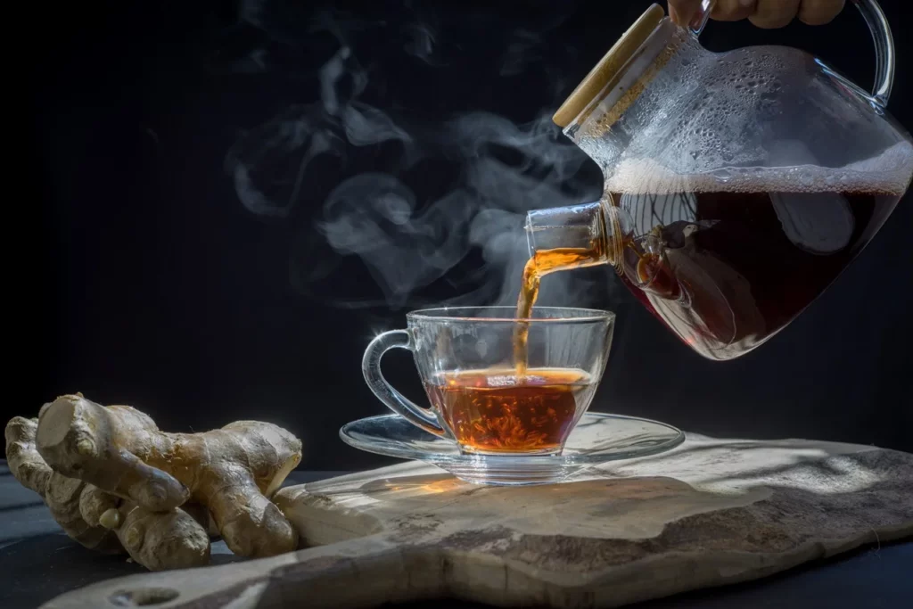pouring ginger tea in a glass kettle into a cup