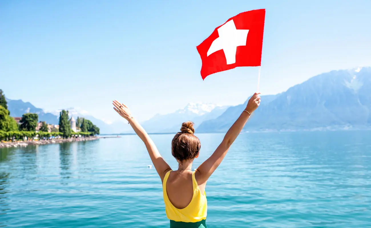 Traveler holding a Swiss flag by Lake Geneva